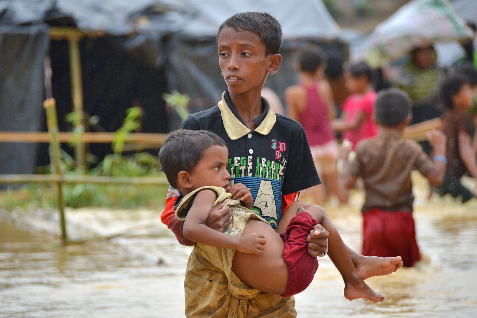 Nach einem Monsun in Bangladesch trägt ein Junge seinen Bruder durch die Wassermassen